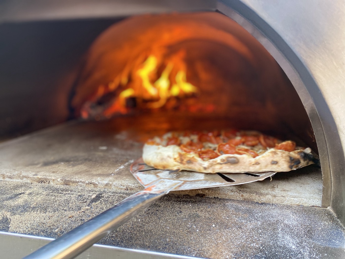 A finished pie with charred crust and fresh toppings.