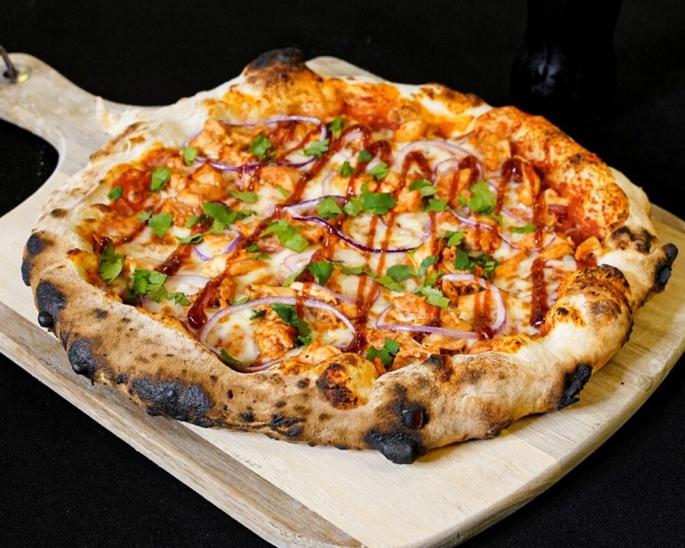 A freshly fired pizza resting on a board.