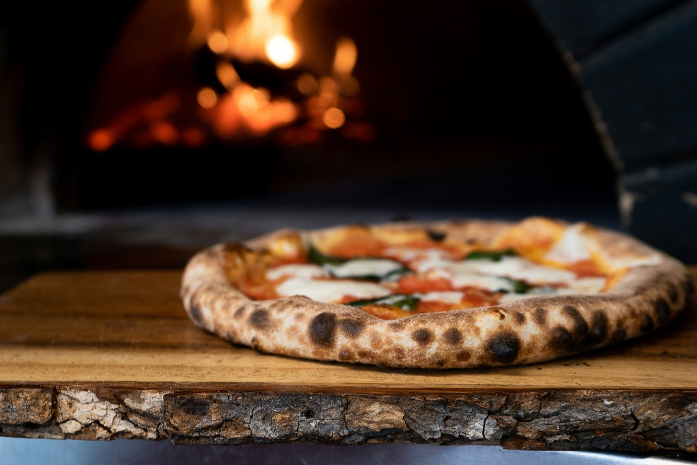 Two pizzas baking inside the glowing wood-fired oven.